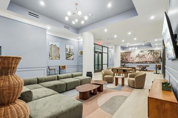 A spacious living room with a large wicker chair and a green sofa.